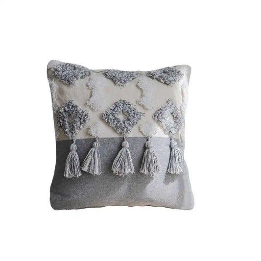 Coussin bohème chic avec pompons et motifs gris et blanc sur fond blanc