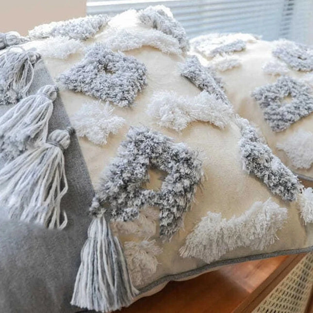 Coussin bohème chic avec pompons et motifs gris et blanc